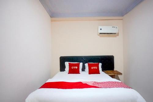 a bedroom with a bed with two red pillows at Hotel O Medan City Center Near Plaza Medan Fair Formerly Waringin Residence in Medan