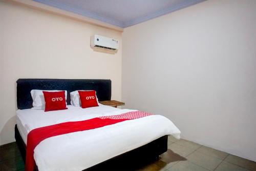 a bedroom with a bed with two red pillows at Hotel O Medan City Center Near Plaza Medan Fair Formerly Waringin Residence in Medan