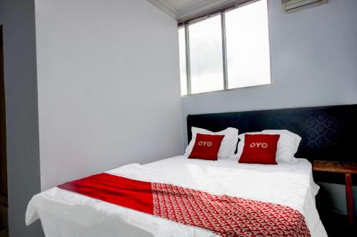 a bedroom with a bed with two red pillows at Hotel O Medan City Center Near Plaza Medan Fair Formerly Waringin Residence in Medan