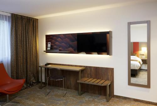 a hotel room with a desk and a flat screen tv at Mercure Belfort Centre in Belfort