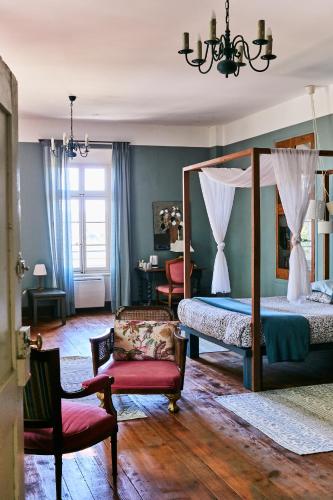 une chambre avec un lit à baldaquin et une chaise dans l'établissement Fontclaire en Provence, à Uchaux