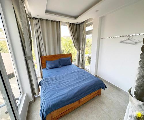 a bedroom with a bed with blue sheets and a window at Otel Hotel Dalat in Da Lat