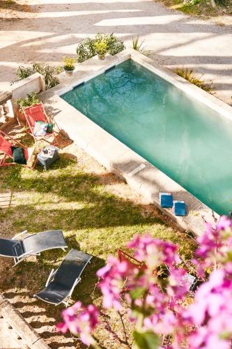 une piscine avec deux chaises longues et des fleurs roses dans l'établissement Fontclaire en Provence, à Uchaux