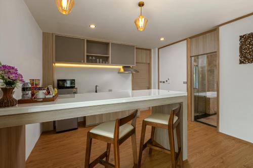 a kitchen with a large counter and two stools at Phunawa Resort Phuket Karon Beach - SHA Plus in Karon Beach