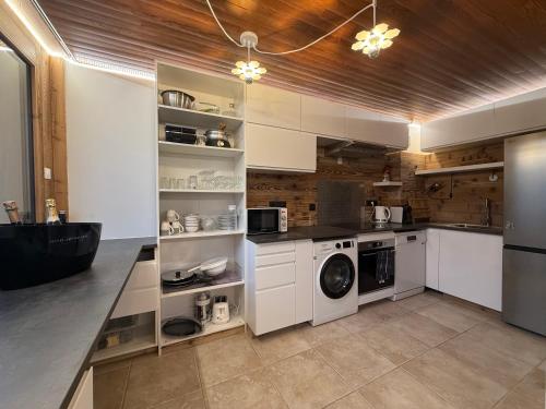 une cuisine avec des armoires blanches et une laveuse et une sécheuse dans l'établissement Meralouva 1650 Domaine de l Ariondaz Courchevel, à Courchevel