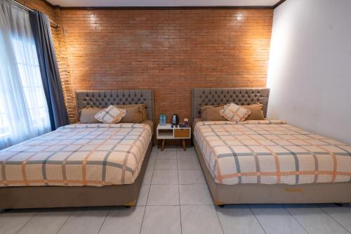 two beds in a room with a brick wall at Kinkeo Borobudur in Magelang