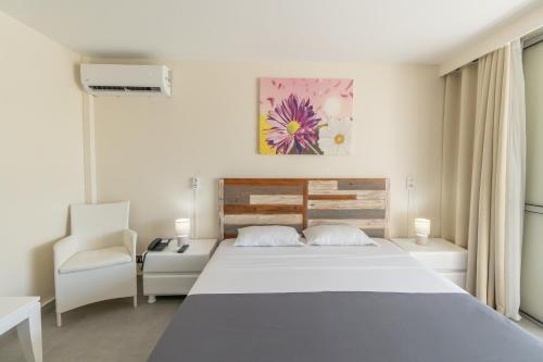 a bedroom with a large white bed and a chair at Canella Beach Hotel in Le Gosier