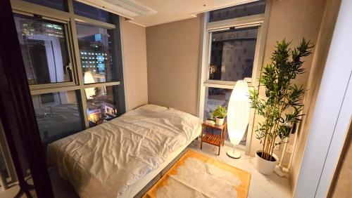 a small bedroom with a bed and two windows at Majestic Seoul Stay Central in Seoul