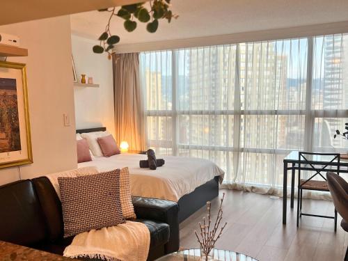 a bedroom with a bed and a couch and a large window at City Retreat With Views in the Heart of Downtown in Vancouver