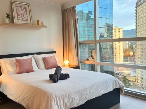a bedroom with a large bed with a large window at City Retreat With Views in the Heart of Downtown in Vancouver