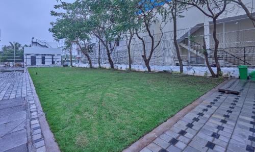 a grassy yard with trees and a building at Grand Continent Mahabalipuram A Sarovar Premiere Affiliate Hotel in Mahabalipuram
