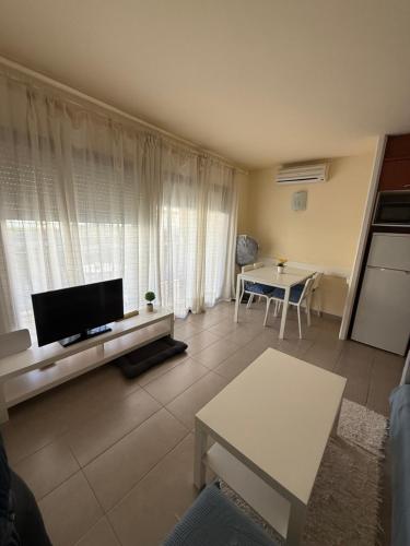 ein Wohnzimmer mit Fernseher und Tisch in der Unterkunft Estartit Jardins del mar 51 in L'Estartit