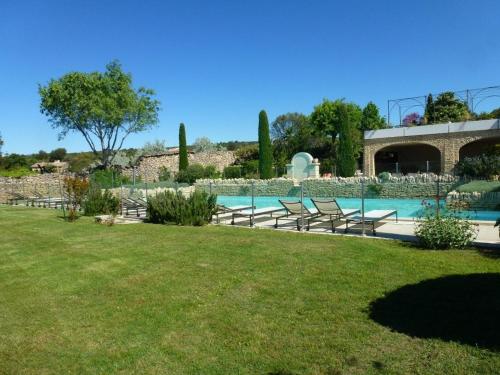 - une piscine dans une cour avec des chaises et un bâtiment dans l'établissement Bastidon de Gordes, à Gordes