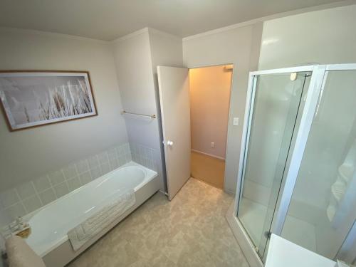 a bathroom with a shower and a bath tub at Central Whangarei Townhouse in Whangarei