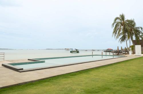 a swimming pool on the beach with the ocean in the background at Sadi Beach House in Telukbakau