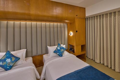a bedroom with two beds with blue and white pillows at Grand Continent Mahabalipuram A Sarovar Premiere Affiliate Hotel in Mahabalipuram