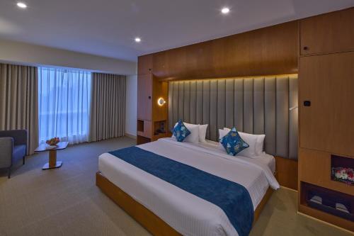 a hotel room with a large bed and a chair at Grand Continent Mahabalipuram A Sarovar Premiere Affiliate Hotel in Mahabalipuram