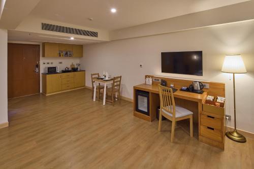 a room with a desk and a kitchen with a table and chairs at Grand Continent Mahabalipuram A Sarovar Premiere Affiliate Hotel in Mahabalipuram