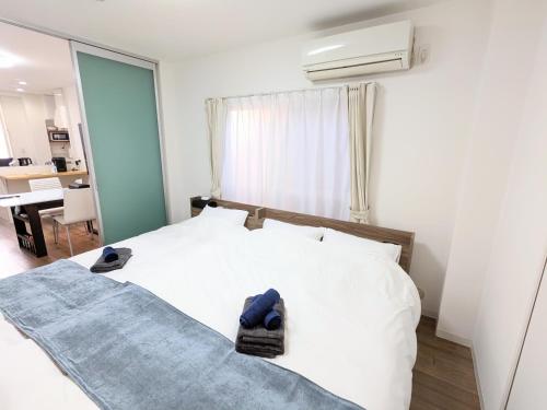 a bedroom with a white bed with blue shoes on it at SEIRYU Bldg in Tokyo
