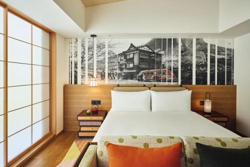 a bedroom with a large bed and a painting on the wall at Hotel Indigo Hakone Gora by IHG in Hakone