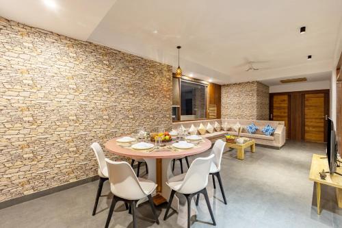 una sala da pranzo e un soggiorno con parete in mattoni di Alaya Stays 4 BHK with Pvt Plunge pool - Lumbini a Udaipur