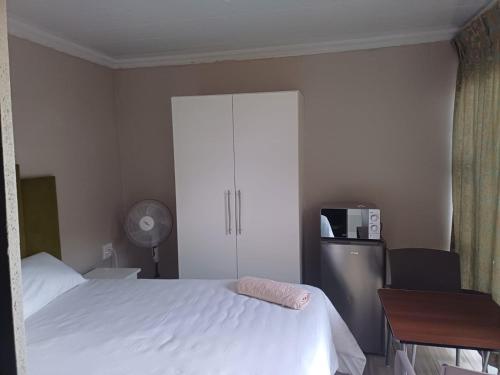 a bedroom with a white bed and a cabinet at Willow's Guesthouse in Vereeniging