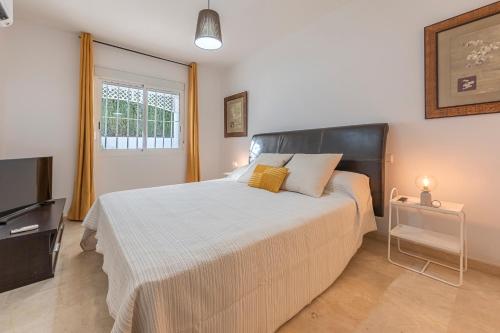 a bedroom with a large bed and a television at DOLMEN GROUP- Jardines Andalucia Banus in Marbella