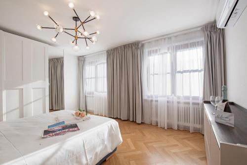 a white bedroom with a bed and a chandelier at Novos Arcadia 501 - Happy Rentals in Lugano