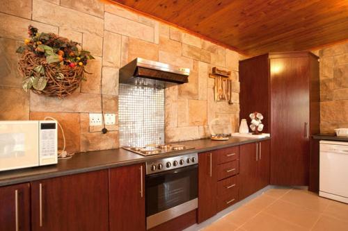 a large kitchen with a stove and a microwave at Quest Bed And Breakfast in Melkbosstrand
