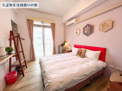 a bedroom with a bed with a red headboard at Jinguann B&B in Hualien City