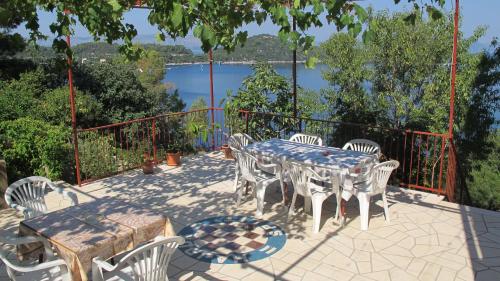 a table and chairs on a patio with a view of a lake at Guest House Ruža in Sobra