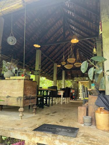 a patio with a table and chairs and a ceiling at Jansen’s Bungalow Sinharaja Rainforest Retreat in Kudawe