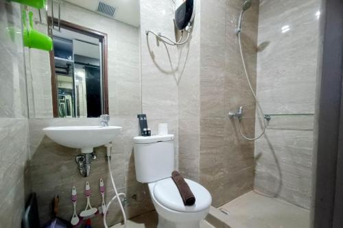 a bathroom with a toilet and a sink and a shower at Relaxing Studio at Vida View Makassar Apartment By Travelio in Pampang