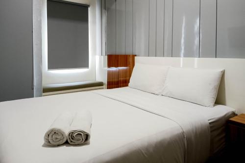 a bedroom with a bed with two towels on it at Relaxing Studio at Vida View Makassar Apartment By Travelio in Pampang