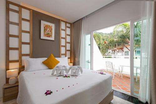 a bedroom with a large white bed and a large window at Phunawa Resort Phuket Karon Beach - SHA Plus in Karon Beach