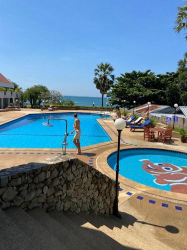 a man is standing next to a swimming pool at Amazing Spacious Seaview Condo in North Pattaya