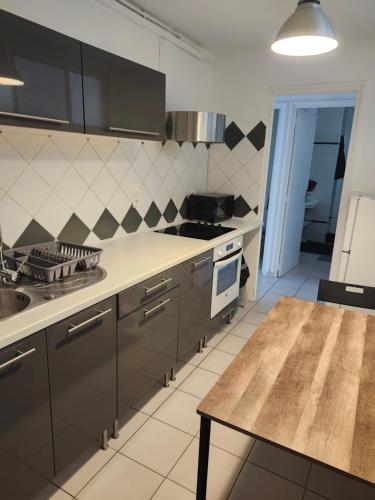 une cuisine avec des armoires noires et une table. dans l'établissement Joli F3 Montpellier proche mer et centre ville, à Montpellier