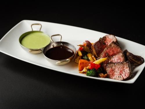 a plate of food with steak and a dipping sauce at Tokyo Bay Shiomi Prince Hotel in Tokyo