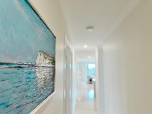 a painting hanging on a wall in a hallway at Little Santorini Retreat - Family Home near Theme Parks in Pimpama