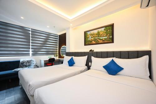 2 letti in camera d'albergo con cuscini blu di Ruby Saigon Hotel - Ben Thanh ad Ho Chi Minh