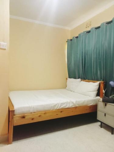 a bed in a room with a green curtain at Mimie's homes in Eldoret