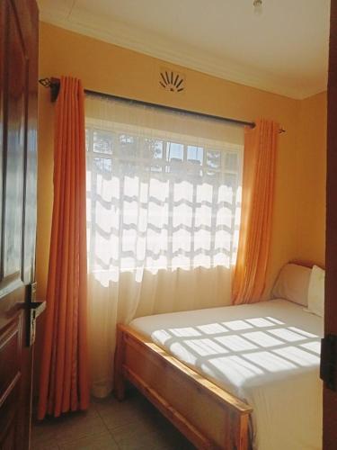 a bedroom with a bed and a window with orange curtains at Mimie's homes in Eldoret
