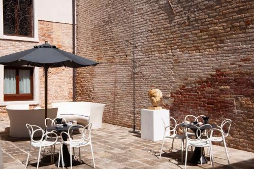 a patio with tables and chairs and an umbrella at Hotel Aquarius Venice - Ascend Collection in Venice