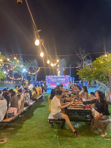 a group of people sitting at tables at night at Mianfarm Bàu trắng glamping in Ấp Nhơn Hòa