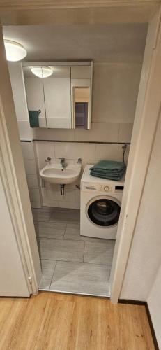 a small bathroom with a sink and a washing machine at Airolo with private parking in Airolo