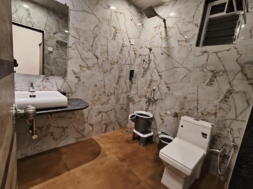 une salle de bain avec des toilettes blanches et un lavabo dans l'établissement Mount Bliss Resort, à Mhasla