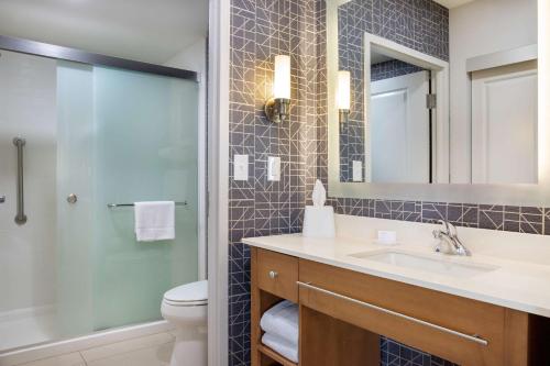 a bathroom with a sink and a toilet and a mirror at Homewood Suites by Hilton Winnipeg Airport - Polo Park in Winnipeg