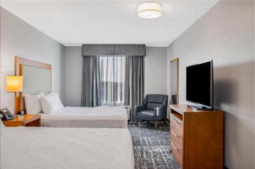 a hotel room with two beds and a flat screen tv at Homewood Suites by Hilton Winnipeg Airport - Polo Park in Winnipeg