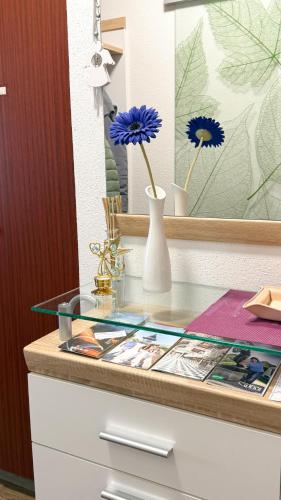 a glass counter with flowers in a vase on a dresser at Komfortables Appartement/Garconniere in Graz für Urlaub und Geschäftsreisen in Graz
