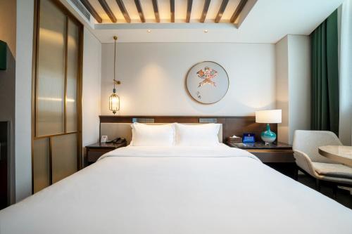a bedroom with a large white bed and a chair at THE YARD HOTEL BEIJING,BianyiFang - steps The Forbidden City - strolling through the imperial gardens is incredibly easy - The guest rooms blend modern comfort with Chinese charm - Peking duck - living in history Your Beijing adventure begins here in Beijing